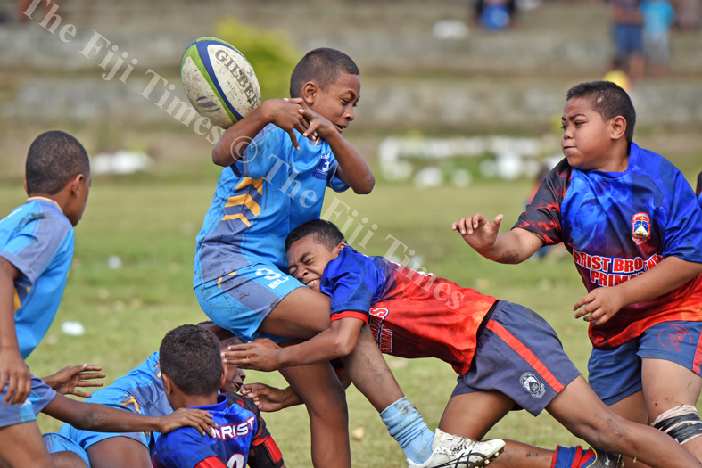 Ronald Tom of John Wesley Primary School losses the ball in a tackle from the Marist Suva Street primary during the Suva Kaji rugby at Gospel grounds yesterday. Picture: RAMA